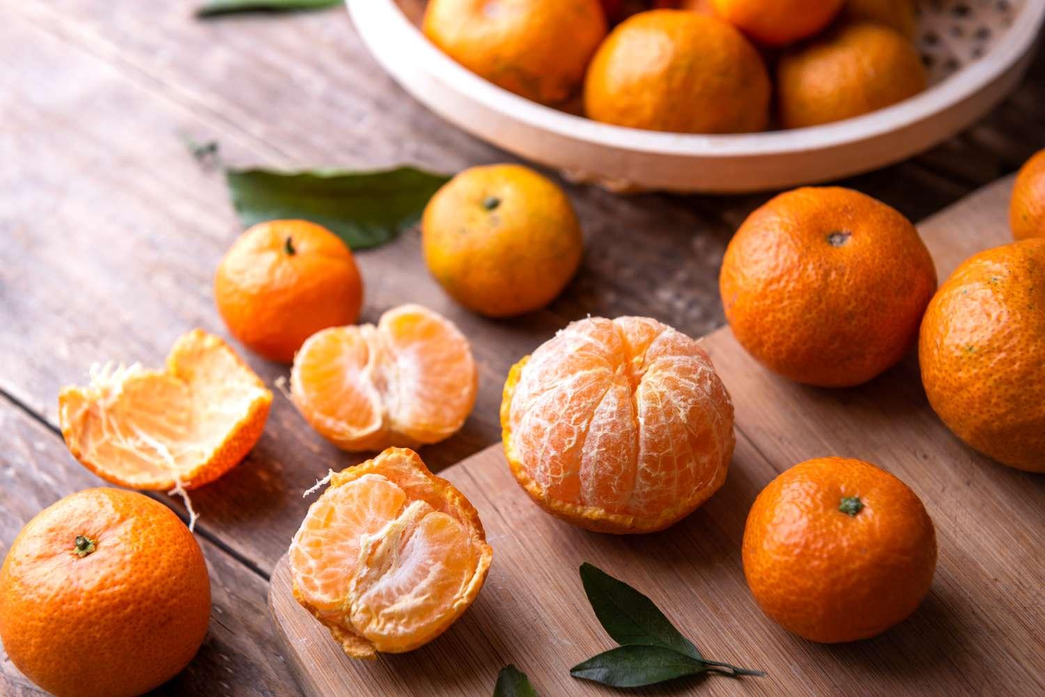 A vibrant, freshly peeled tangerine displaying its juicy segments against a background of whole tangerines and mandarins, highlighting the bright orange color and enticing texture of these citrus fruits.
