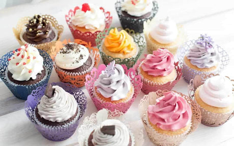 Close-up of a delicious cupcake with pink frosting, sprinkles, and a decorative flower on top