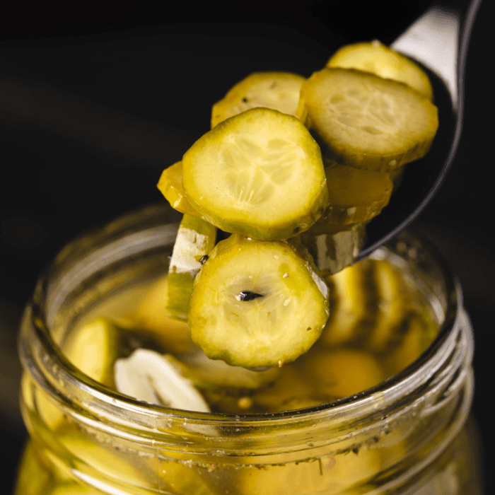 "A glass jar filled with green olives, sealed with a metal lid."