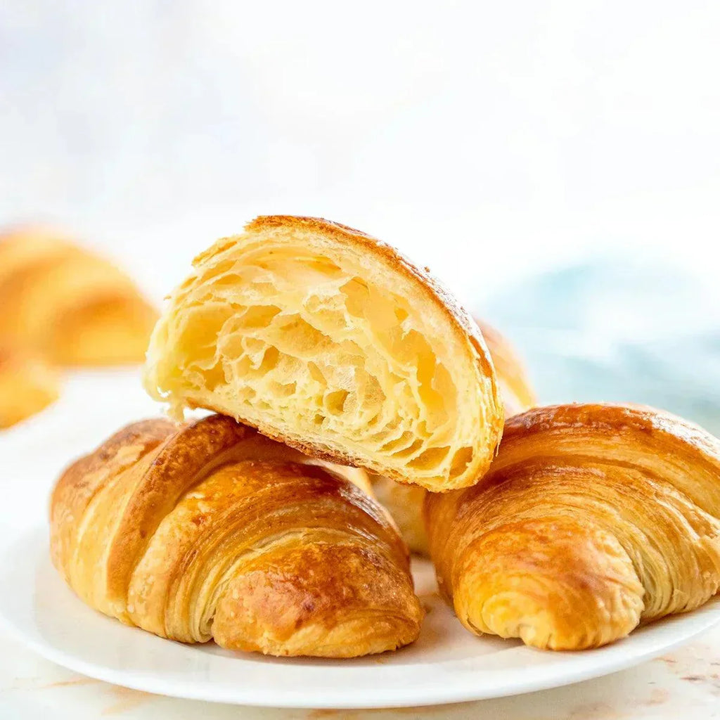 Image showing freshly baked croissants on a wooden cutting board with a cup of coffee in the background